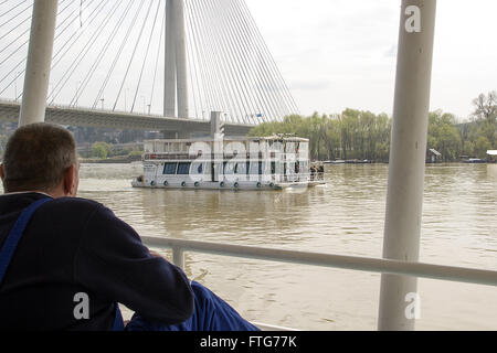 La rivière Sava, Belgrade, Serbie - Senior sailor regarde le bateau de tourisme en passant par d'une péniche ancrée Banque D'Images