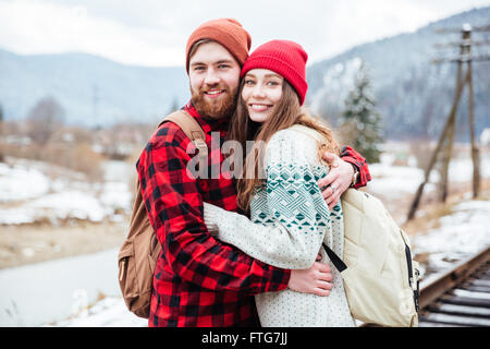 Portrait of happy young couple avec sacs à dos hugging in mountains Banque D'Images