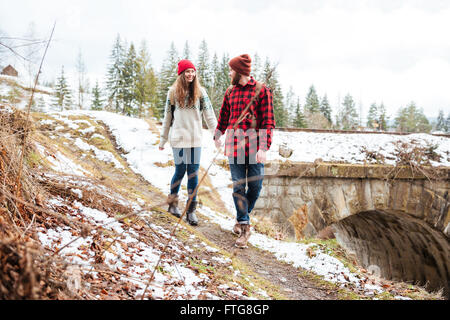 Beautiful happy young couple holding hands and walking outdoors in winter ensemble Banque D'Images