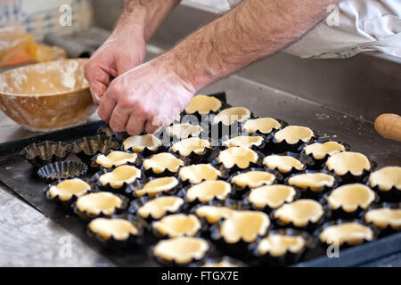 Close Up de mâles non identifiables Baker Preparing Pastry pour les petites tartelettes - Pâtisserie Maison d'aplatissement dans Tarte individuels ébouriffé Banque D'Images
