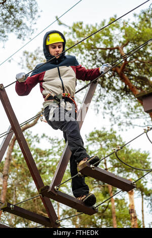 Adolescent sur un cours à un parc d'aventure avec des protections Banque D'Images