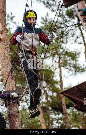 Adolescent sur un cours à un parc d'aventure avec des protections Banque D'Images