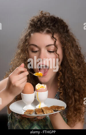 Young Girl eating œufs durs avec « soldiers' pour le petit déjeuner Banque D'Images