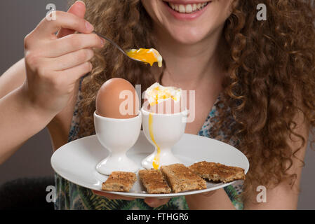 Young Girl eating œufs durs avec « soldiers' pour le petit déjeuner Banque D'Images