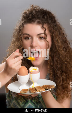 Young Girl eating œufs durs avec « soldiers' pour le petit déjeuner Banque D'Images