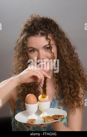 Young Girl eating œufs durs avec « soldiers' pour le petit déjeuner Banque D'Images