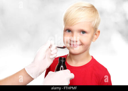 Un enfant avec un médecin, un traitement pour la grippe. Un délicieux sirop, le garçon boire un remède pour le rhume. Banque D'Images