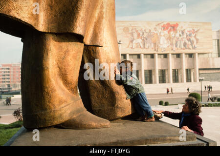 Jeune garçon, encouragé par sa mère, embrassant les pieds de la statue d'Enver Hoxha, le fondateur de l'état communiste, Tirana, 1990 Banque D'Images