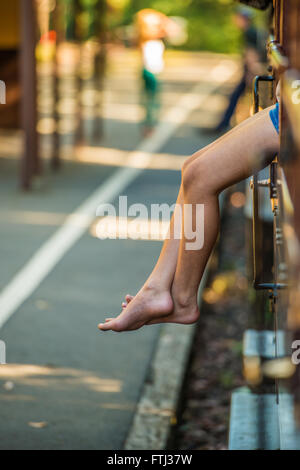 Jeune fille assise sur le bord du train Banque D'Images