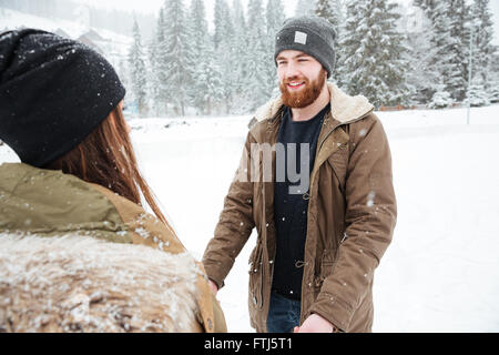 Couple heureux s'amuser en plein air avec de la neige sur l'arrière-plan Banque D'Images