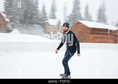 Homme heureux le patin à glace en plein air avec de la neige sur l'arrière-plan Banque D'Images