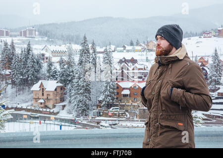 Beau jeune homme sérieux et permanent de profiter de la vue sur mountain resort Banque D'Images