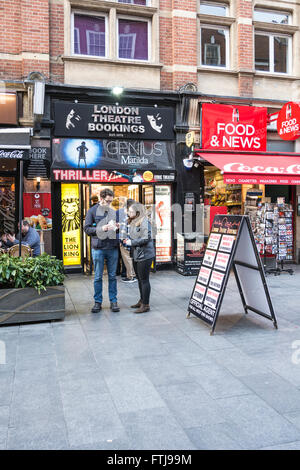 Un couple de vérifier leurs billets à partir de la billetterie du centre de Londres, UK Banque D'Images