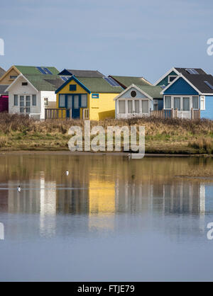 Une rangée de cabines de plage et leurs réflexions dans une lagune de Christchurch Harbour à Hengistbury Head, Bournemouth, Dorset, England, UK Banque D'Images