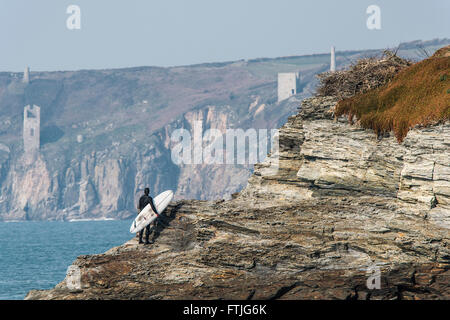 Un internaute se dresse sur un promontoire rocheux et donne sur la côte de Cornouailles. Banque D'Images