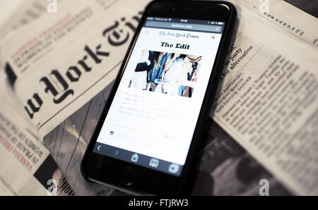 ILLUSTRATION - une page web qui permet aux utilisateurs de s'abonner à la lettre d'information "l'edit' par le New York Times peut être vu sur l'écran d'un téléphone mobile à Berlin, Allemagne, 04 mars 2016, avec une édition imprimée du International New York Times, représenté à l'arrière-plan. Photo : HENRIK JOSEF BOERGER/dpa Banque D'Images