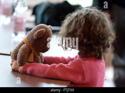 Berlin, Allemagne. Mar 29, 2016. Une jeune fille jouant avec son ours en peluche dans un centre d'hébergement d'urgence des réfugiés à Berlin, Allemagne, 29 mars 2016. Photo : Britta Pedersen/dpa/Alamy Live News Banque D'Images