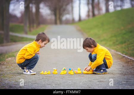 Deux adorables enfants, frères, Garçon jouant dans parc avec des canards en caoutchouc, plaisir. Le bonheur de la petite enfance concept Banque D'Images