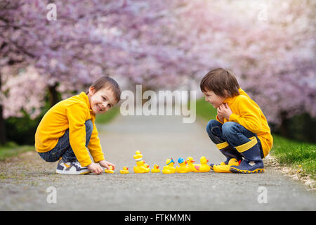 Deux adorables enfants, frères, Garçon jouant dans parc avec des canards en caoutchouc, plaisir. Le bonheur de la petite enfance concept Banque D'Images