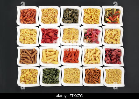 Les pâtes sèches, y compris les variétés de couleur alimentaire spaghetti dans la porcelaine chine bols sur fond gris Banque D'Images