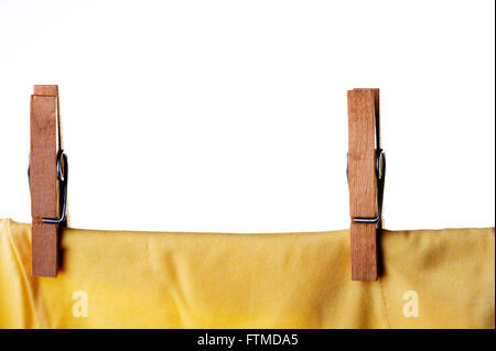 Vêtements en bois peg ou l'axe fixant un t-shirt jaune sur les vêtements en ligne. Banque D'Images