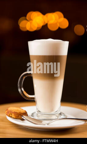 Caffe café macchiato boisson dans un verre, servi dans un café sur une soucoupe d'un biscuit. Banque D'Images