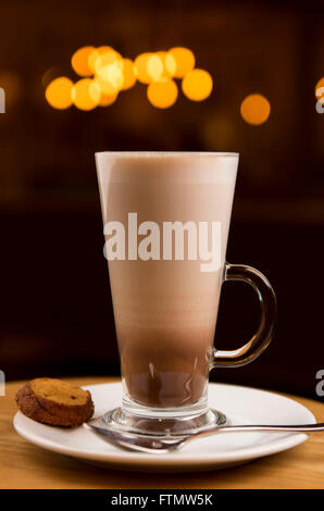 Caffe café macchiato boisson dans un verre, servi dans un café sur une soucoupe d'un biscuit. Banque D'Images