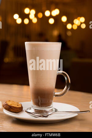 Caffe café macchiato boisson dans un verre, servi dans un café sur une soucoupe d'un biscuit. Banque D'Images