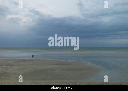 Couple éloigné marche sur une plage de sable déserte, Normandie, France Banque D'Images