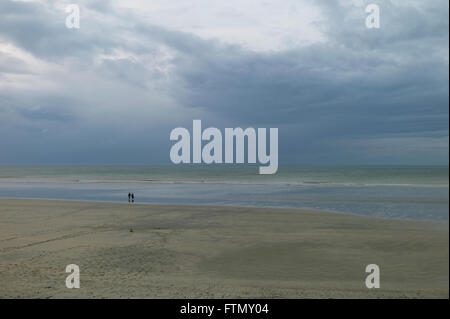 Couple éloigné marche sur une plage de sable déserte, Normandie, France Banque D'Images