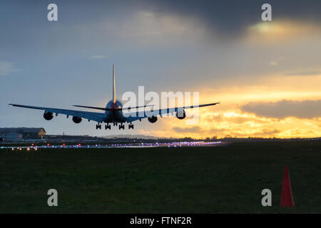 Un Airbus A380 atterrit sur la piste 27R alors que le soleil se couche à l'aéroport de Londres Heathrow. Banque D'Images