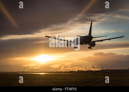 Un Boeing 777-300 de British Airways terres comme le soleil illumine les nuages derrière gauche Banque D'Images