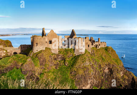 Ruines du château de Dunluce dans le comté d'Antrim, Irlande du Nord, Royaume-Uni, avec l'avis de Portrush resort sur la gauche Banque D'Images