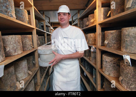 Daylesford Creamery fromager James McCall avec son seul fromage de Gloucester dans la main,avec Double Gloucester fromages sur des étagères Banque D'Images