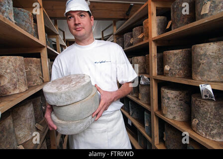 Daylesford Creamery fromager James McCall avec son seul fromage de Gloucester dans la main,avec Double Gloucester fromages sur des étagères Banque D'Images