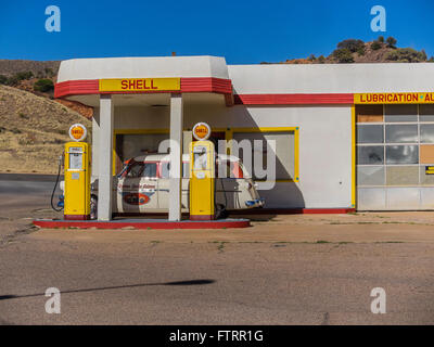 Classic 1950 Station Shell peint en jaune et rouge en couleurs et de Shell avec un 1952 Ford station wagon garé en face. Banque D'Images