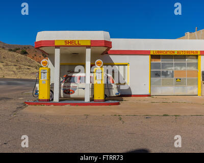 Classic 1950 Station Shell peint en jaune et rouge en couleurs et de Shell avec un 1952 Ford station wagon garé en face. Banque D'Images