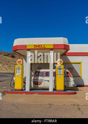 Classic 1950 Station Shell peint en jaune et rouge en couleurs et de Shell avec un 1952 Ford station wagon garé en face. Banque D'Images