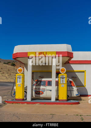 Classic 1950 Station Shell peint en jaune et rouge en couleurs et de Shell avec un 1952 Ford station wagon garé en face. Banque D'Images