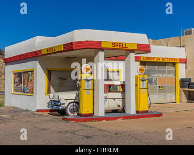 Classic 1950 Station Shell peint en jaune et rouge en couleurs et de Shell avec un 1952 Ford station wagon garé en face. Banque D'Images