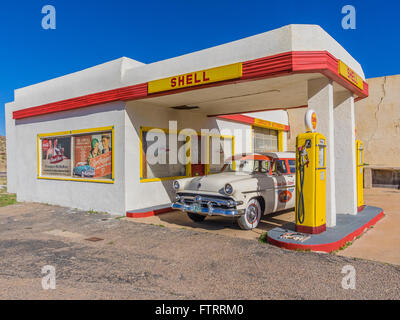 Classic 1950 Station Shell peint en jaune et rouge en couleurs et de Shell avec un 1952 Ford station wagon garé en face. Banque D'Images