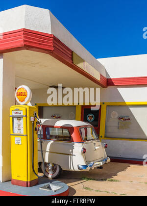 Classic 1950 Station Shell peint en jaune et rouge en couleurs et de Shell avec un 1952 Ford station wagon garé en face. Banque D'Images