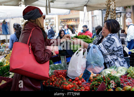 Un client, gauche, paie pour son achat à partir d'un étal de fruits et légumes au marché de plein air à Rome, Italie Banque D'Images