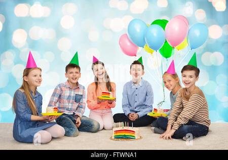 Heureux les enfants en chapeaux de fête avec gâteau d'anniversaire Banque D'Images