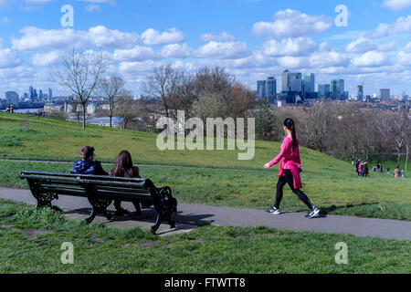 Jeune femme dans des vêtements d'exercice marche dernières couple sitting on bench, le Parc de Greenwich, London, UK Banque D'Images