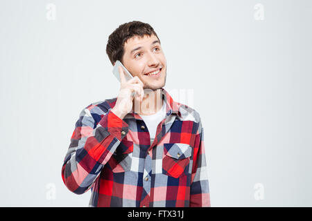 Smiling casual man parler au téléphone et jusqu'à la isolé sur fond blanc Banque D'Images