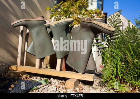 Quatre paires de bottes wellington ou la gomme stockés sur un support à bottes à l'extérieur d'une porte avant pour les garder au sec et propre. Banque D'Images