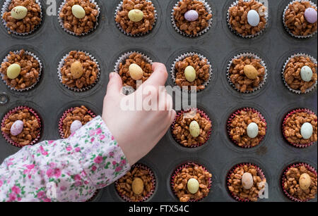 Une main d'enfant choisir un chocolat de Pâques gâteau krispy Banque D'Images