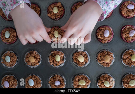 Une main d'enfant choisir un chocolat de Pâques gâteau krispy Banque D'Images