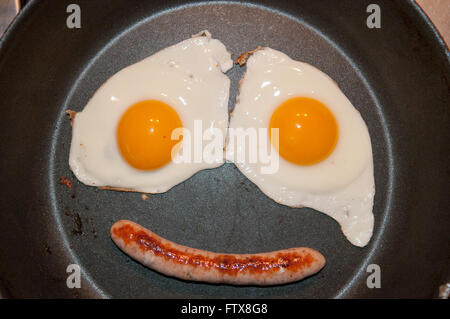 Deux œufs au plat et d'une saucisse faire un visage dans la casserole Banque D'Images